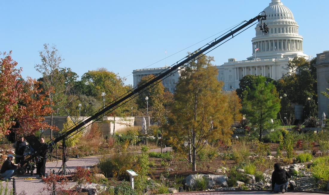 Camera crew with very large jib photographing gardens. U.S. Capitol in the background.